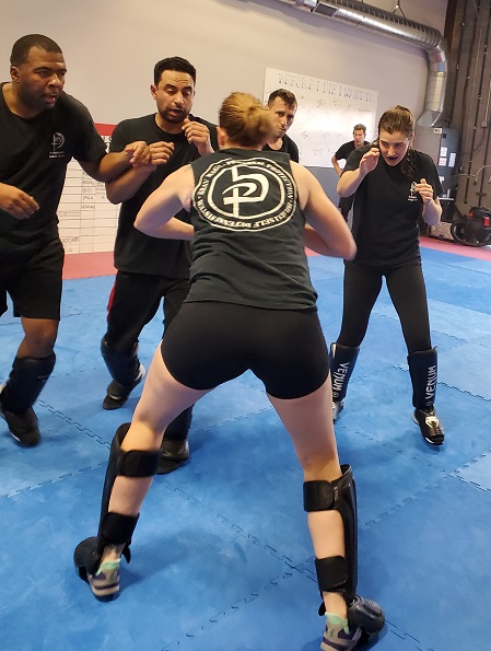 Picture from Warriors Krav Online showing a girl about to defend against 4 attackers
