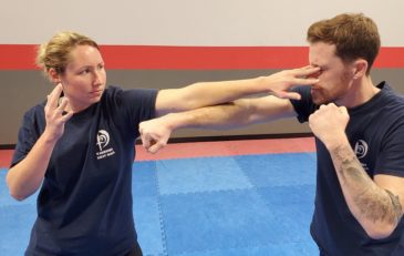A picture of a female student doing an eye strike technique onto someone illustrating the efficacy of learning to strike